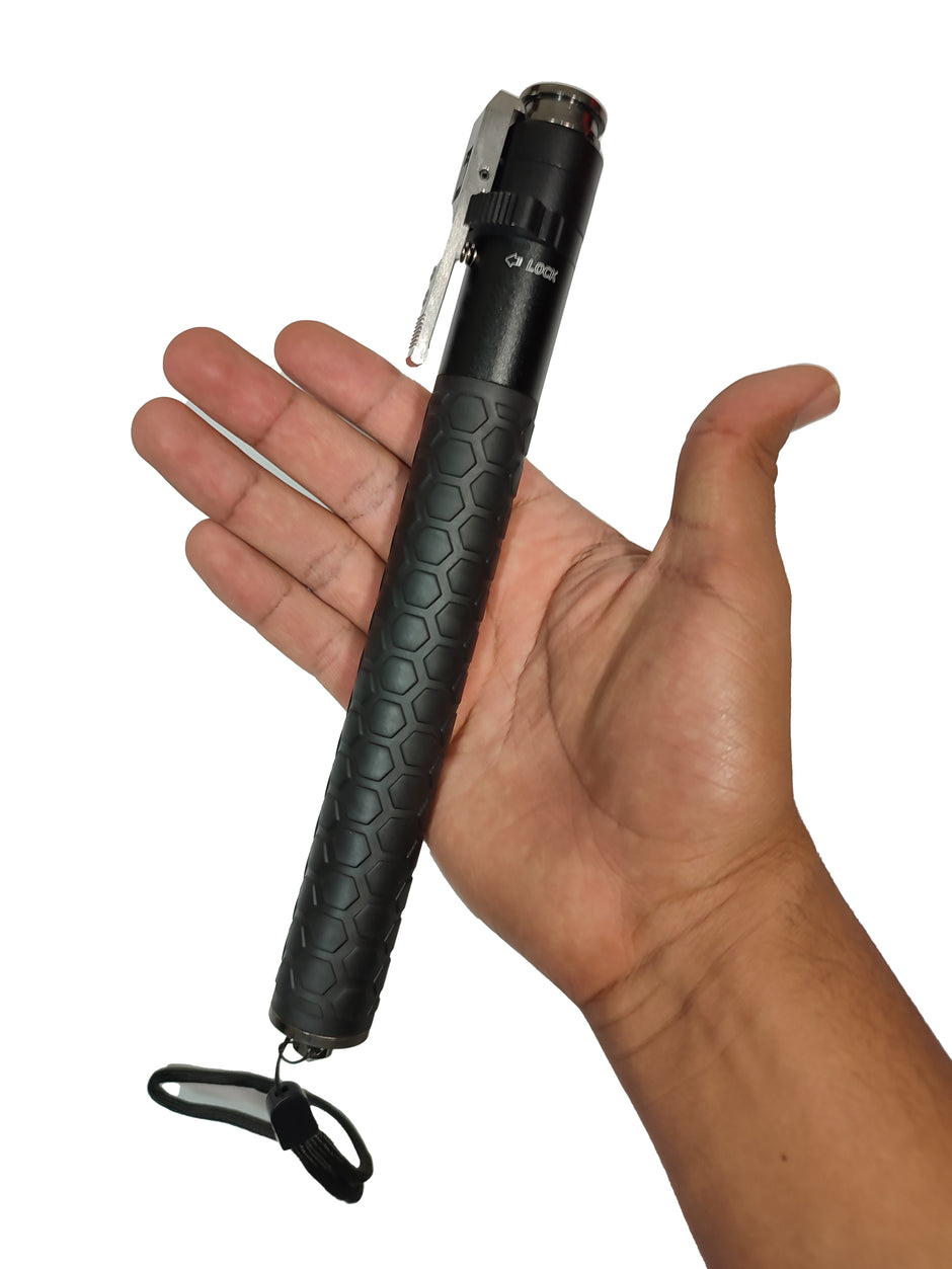 Bastón retráctil automático de mango anti derrapante con formas de hexágonos seguro para evitar aperturas y botón de apertura automático con ropa y cristales en la parte inferior guardado exhibido en un fondo blanco sobre la palma de una mano